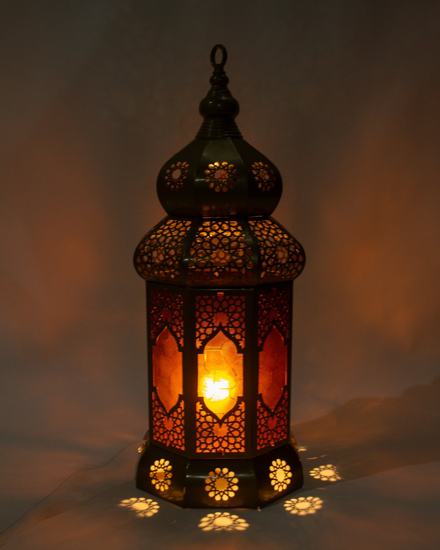 Decorative lantern with intricate patterns and a warm glow on a dark background