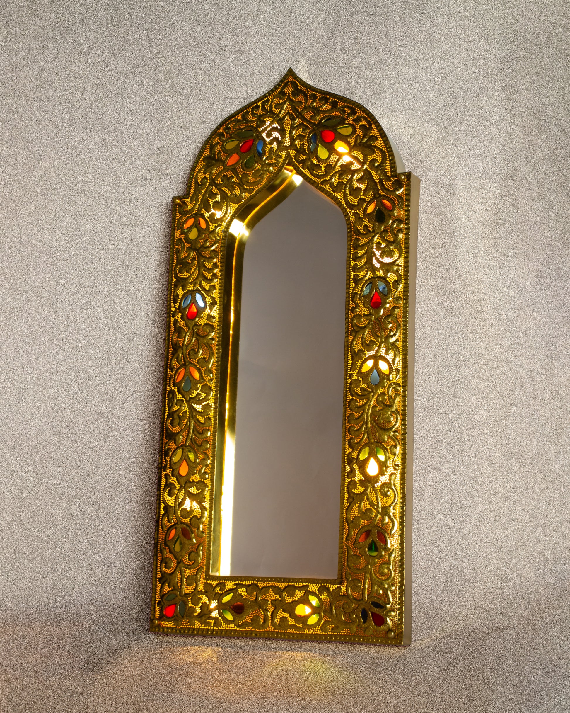 Decorative Hand-Hammered  gold mirror with Glass inlay accents on a plain background