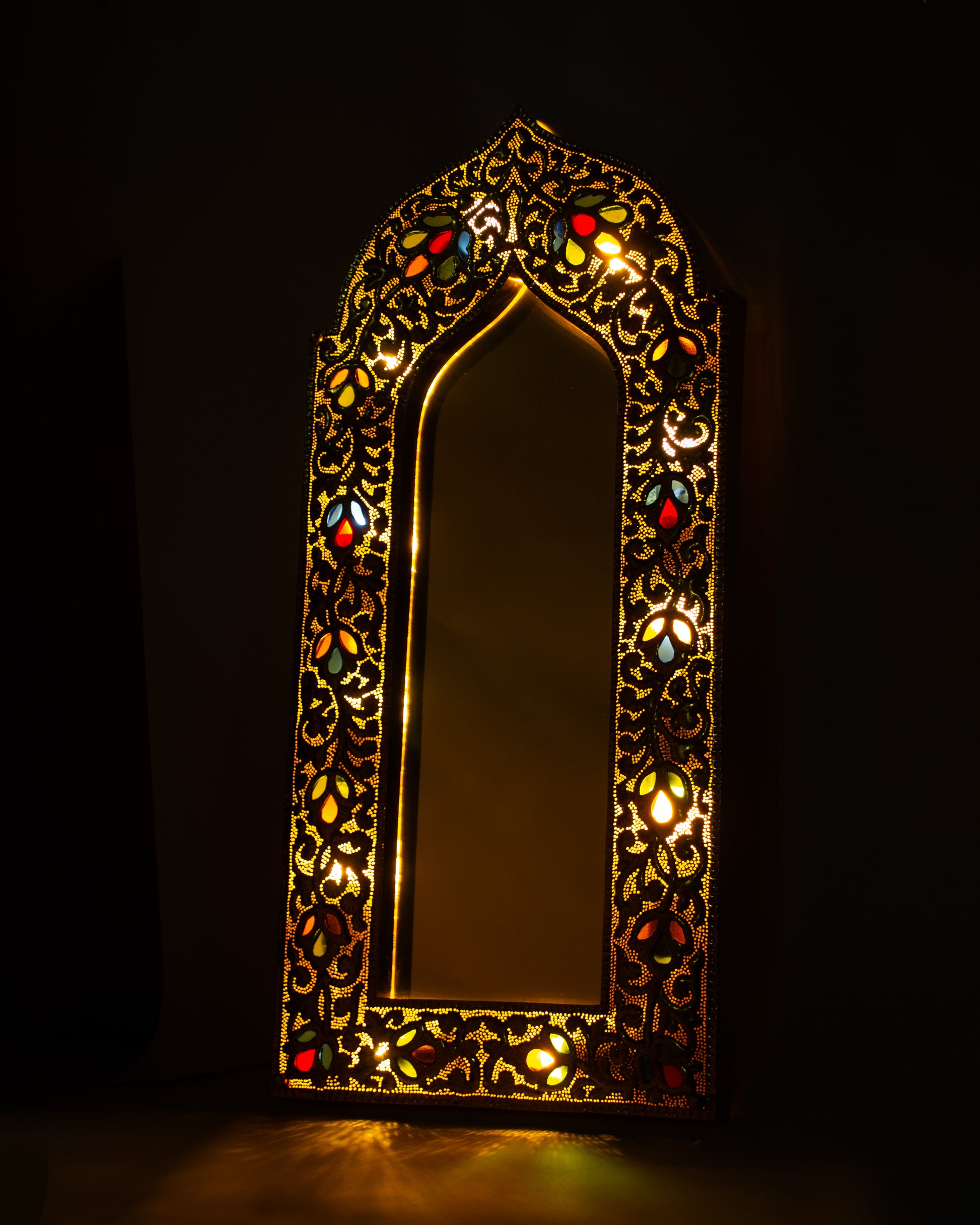 light up Decorative hand-hammered  wall mirror with intricate patterns and colorful glass inlay on a dark background